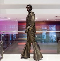 a man in a gold suit standing in a lobby