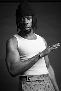 a black and white photo of a man with dreadlocks