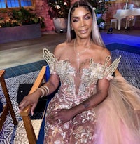 a woman sitting on a chair in a gold gown