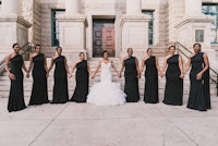 a bride and her bridesmaids pose in front of a building