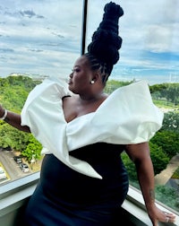 a woman in a white dress standing in front of a window