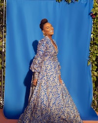 a woman in a blue dress posing in front of a blue backdrop