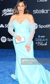 a woman in a blue dress is standing on the blue carpet at the stella awards