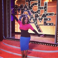 a woman posing in front of a match game sign